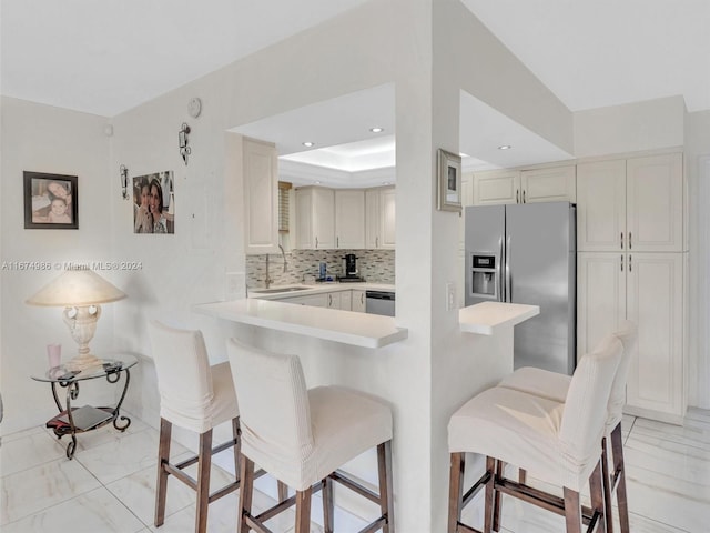 kitchen featuring stainless steel appliances, backsplash, sink, a breakfast bar area, and kitchen peninsula