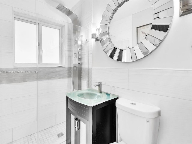 bathroom with a shower with door, vanity, toilet, and tile walls