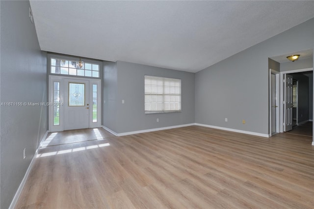 entryway with plenty of natural light, an inviting chandelier, and light hardwood / wood-style flooring