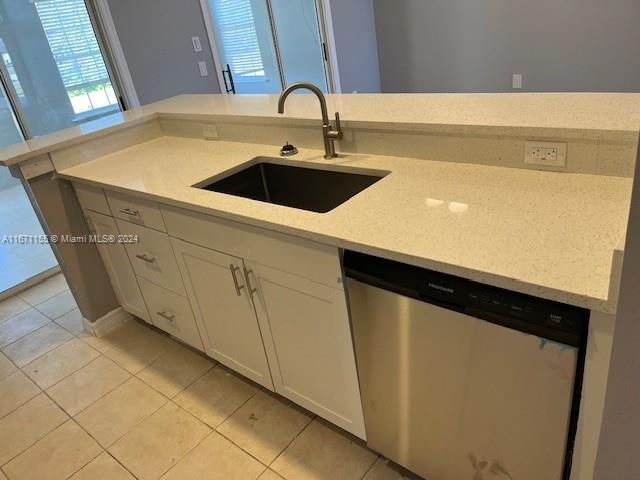 13592 Clara Ln, Port Charlotte, FL 33981 - kitchen featuring dishwasher, a sink, white cabinets, light tile patterned floors, and light stone countertops