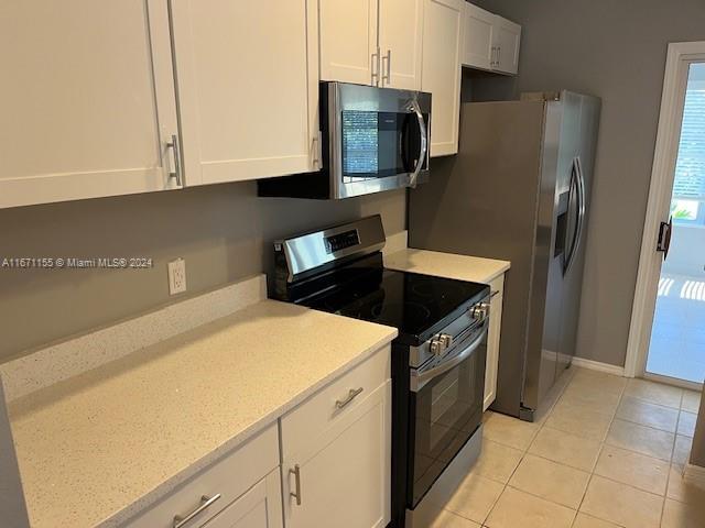 kitchen featuring light tile patterned floors, white cabinetry, and appliances with stainless steel finishes