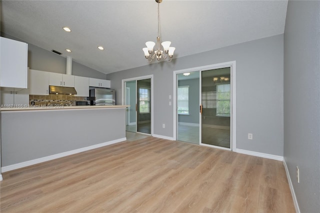 kitchen with white cabinetry, hanging light fixtures, light hardwood / wood-style flooring, vaulted ceiling, and appliances with stainless steel finishes