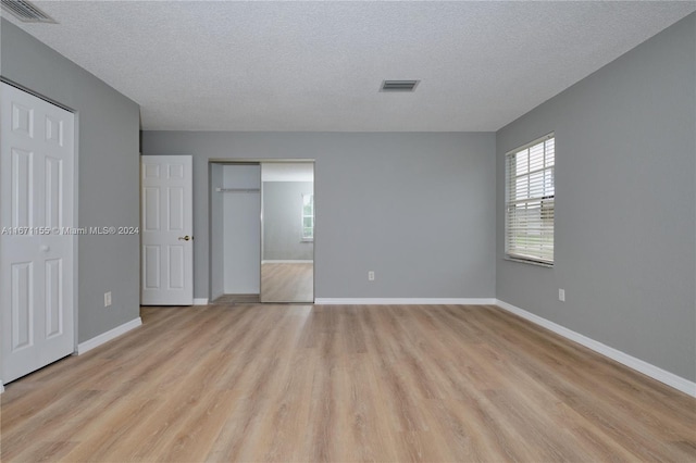 unfurnished bedroom with a textured ceiling and light wood-type flooring