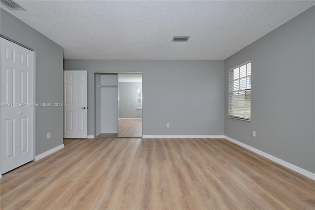 13592 Clara Ln, Port Charlotte, FL 33981 - unfurnished bedroom with light wood finished floors, a textured ceiling, and baseboards