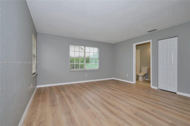 unfurnished room featuring a textured ceiling and light wood-type flooring