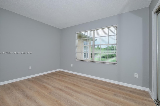 unfurnished room with light hardwood / wood-style flooring and a textured ceiling