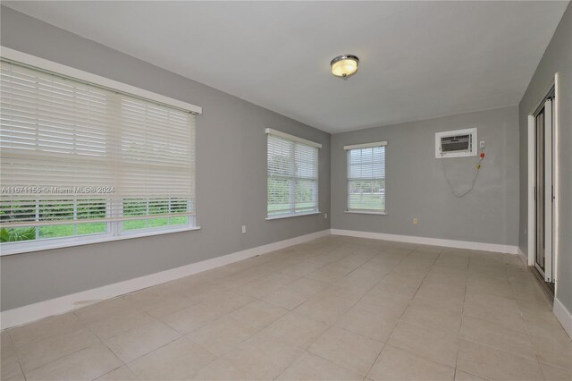 13592 Clara Ln, Port Charlotte, FL 33981 - empty room with an AC wall unit, baseboards, and light tile patterned floors