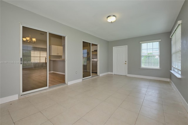 empty room with light tile patterned floors and a chandelier