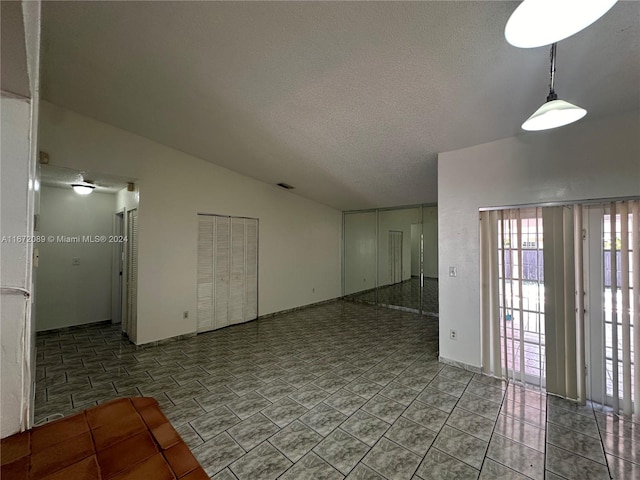 empty room featuring a textured ceiling and lofted ceiling