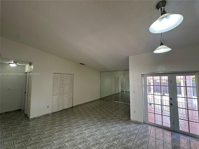 spare room featuring french doors, a textured ceiling, and lofted ceiling