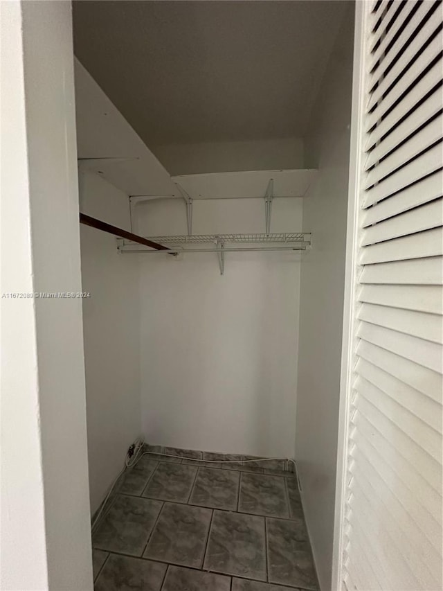 walk in closet with dark tile patterned floors