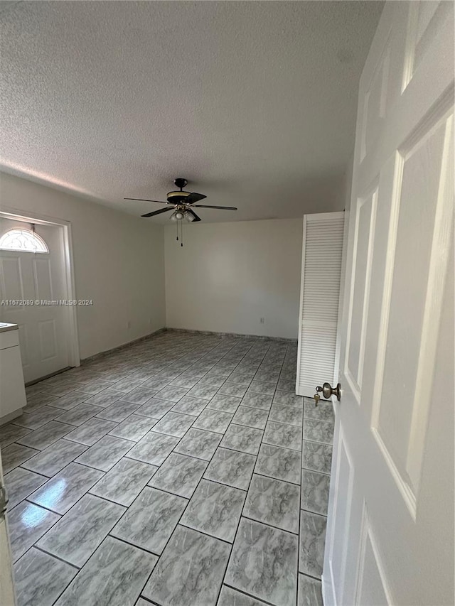 unfurnished room with a textured ceiling and ceiling fan