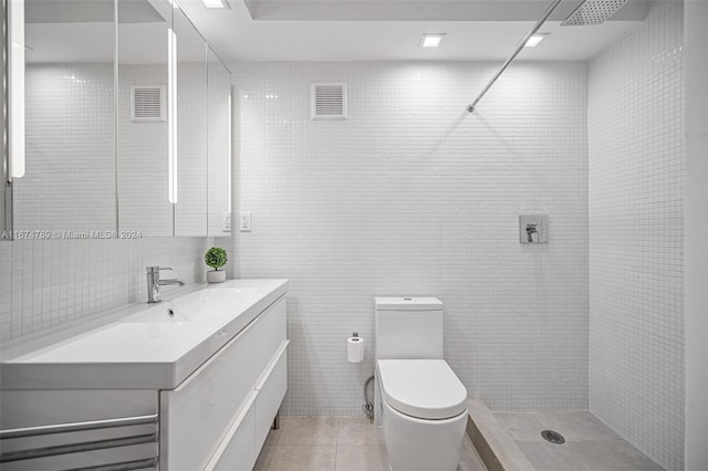 bathroom with vanity, toilet, tile walls, and a tile shower