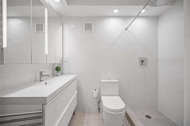 bathroom with vanity, tile walls, a tile shower, toilet, and tile patterned flooring