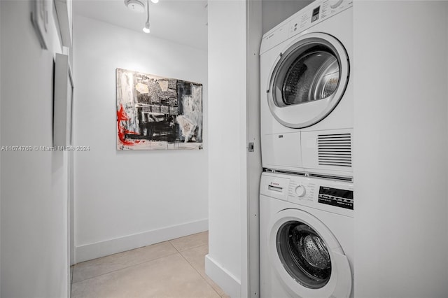 washroom with baseboards, stacked washer / dryer, laundry area, and light tile patterned floors