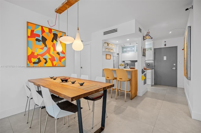 dining space with baseboards, visible vents, and light tile patterned floors