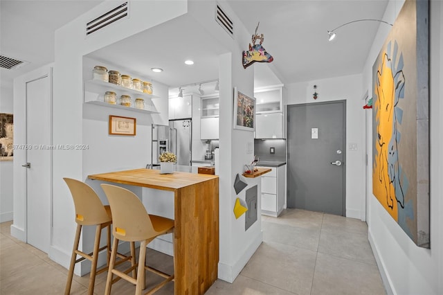 kitchen featuring high quality fridge, visible vents, butcher block countertops, white cabinetry, and open shelves