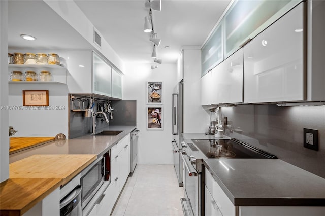 kitchen with appliances with stainless steel finishes, white cabinetry, sink, and light tile patterned floors