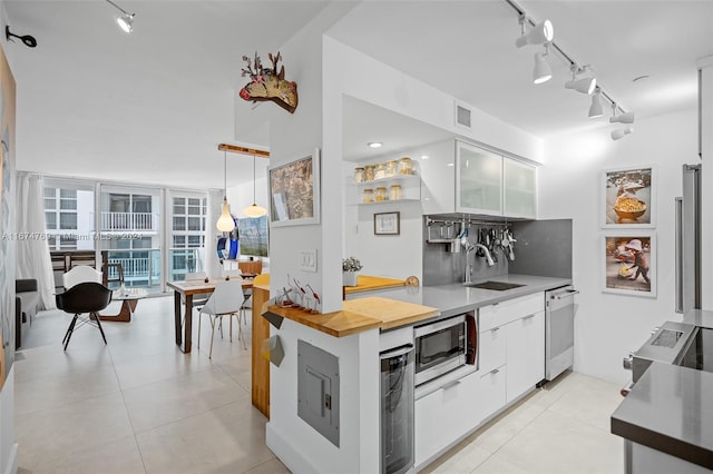 kitchen featuring stainless steel appliances, sink, pendant lighting, light tile patterned floors, and white cabinetry