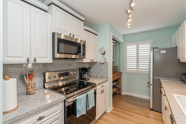 kitchen featuring decorative backsplash, appliances with stainless steel finishes, white cabinets, and light hardwood / wood-style floors