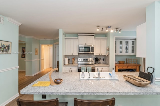 kitchen with a kitchen bar, stainless steel appliances, wood-type flooring, and tasteful backsplash