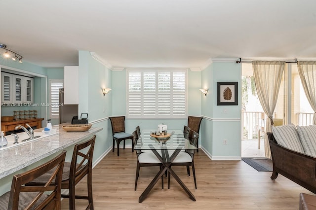 dining area featuring crown molding, sink, and light wood-type flooring