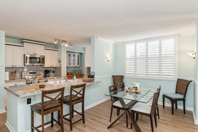 19655 E Country Club Dr Unit 6401, Aventura, FL 33180 - kitchen with appliances with stainless steel finishes, tasteful backsplash, light wood-style floors, a sink, and a kitchen bar