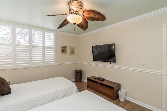 bedroom with crown molding, hardwood / wood-style floors, and ceiling fan