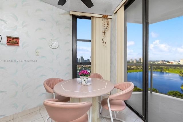 dining space featuring a water view, ceiling fan, floor to ceiling windows, light tile patterned floors, and a textured ceiling