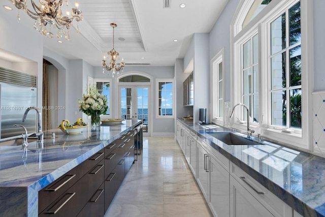 kitchen with stainless steel built in fridge, white cabinets, dark brown cabinets, french doors, and sink