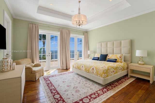 bedroom featuring french doors, access to outside, a tray ceiling, ornamental molding, and hardwood / wood-style floors