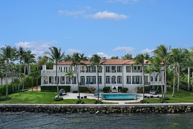 rear view of house featuring a patio area, a yard, a water view, and a balcony