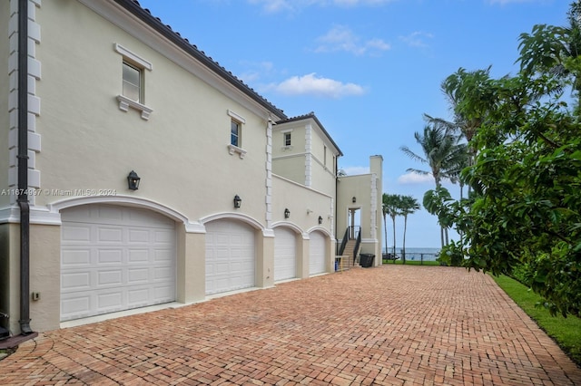 33 Arvida Pkwy, Coral Gables, FL 33156 - view of side of property featuring an attached garage, stucco siding, and decorative driveway