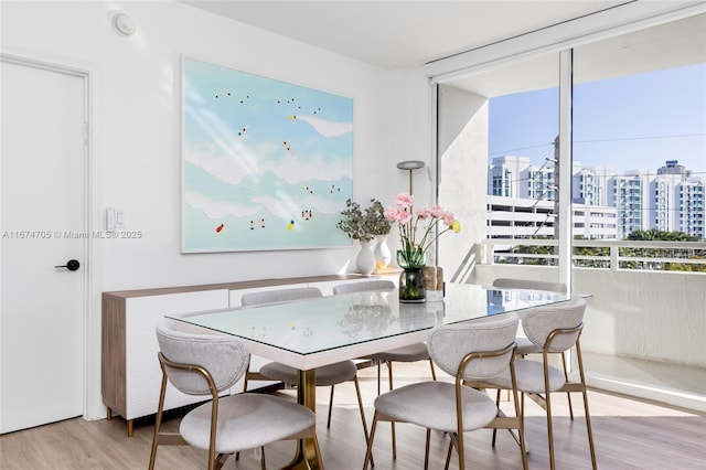 dining space with a wall of windows and light hardwood / wood-style flooring