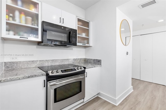 kitchen featuring light wood-type flooring, white cabinetry, electric range, and light stone countertops