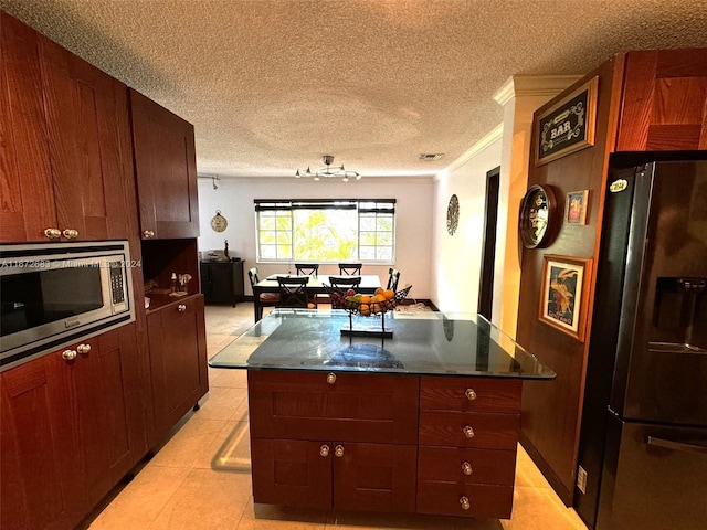 kitchen featuring fridge, ornamental molding, light tile patterned floors, a center island, and stainless steel microwave