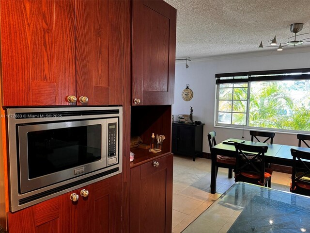 kitchen featuring a textured ceiling, stainless steel microwave, and light tile patterned flooring