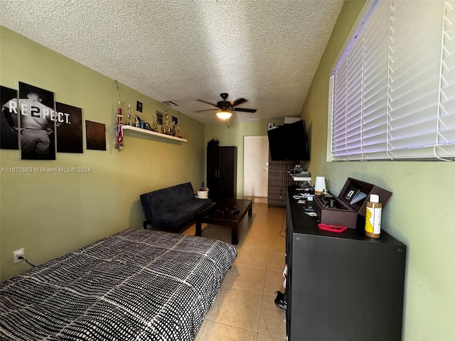 tiled bedroom with ceiling fan and a textured ceiling