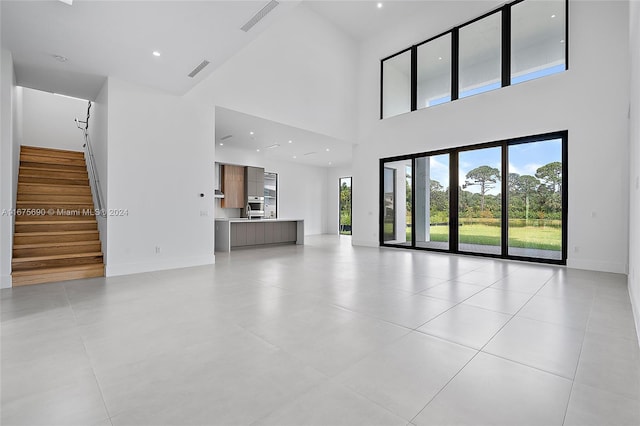 unfurnished living room featuring a towering ceiling and light tile patterned floors