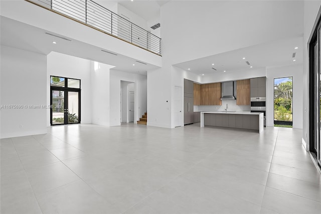 unfurnished living room featuring sink, a high ceiling, french doors, and light tile patterned floors