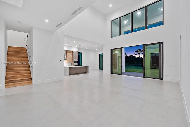 unfurnished living room featuring a towering ceiling and light tile patterned floors