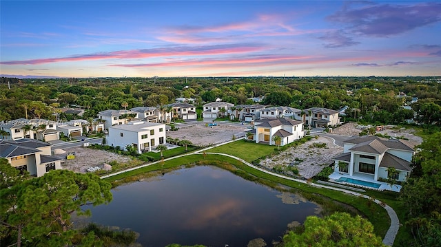 aerial view at dusk featuring a water view