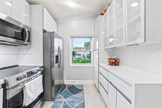 kitchen featuring lofted ceiling, stainless steel appliances, white cabinets, crown molding, and light hardwood / wood-style flooring