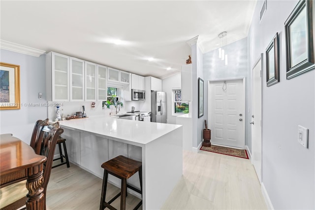 kitchen featuring white cabinets, appliances with stainless steel finishes, crown molding, and kitchen peninsula