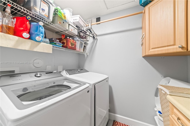 clothes washing area with washing machine and dryer and cabinets