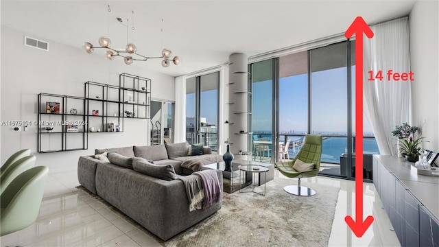 tiled living room featuring a water view, a wall of windows, and a notable chandelier