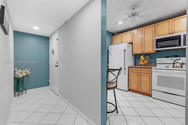 kitchen with dark stone countertops, white appliances, light brown cabinets, and light tile patterned floors