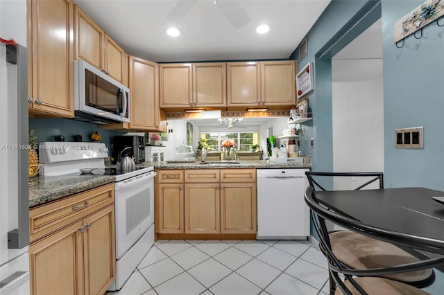 kitchen with stainless steel appliances, dark stone counters, light tile patterned floors, and ceiling fan