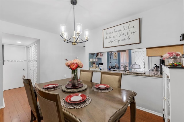 dining room with sink, an inviting chandelier, and light hardwood / wood-style flooring