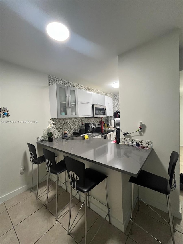 kitchen with sink, appliances with stainless steel finishes, kitchen peninsula, and white cabinetry